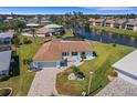 Aerial view of a waterfront home with a lush green lawn, screened in pool, and paved driveway at 1714 Coral Sands Ct, Venice, FL 34293