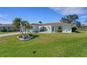 Well-maintained home featuring an arched entryway, a lush green lawn, and mature palm trees in the front yard at 1714 Coral Sands Ct, Venice, FL 34293