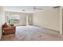 Spacious living room with neutral carpet, ceiling fan, and large front window at 4223 Oakhurst E Cir # 3025, Sarasota, FL 34233