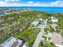 An aerial view shows the property lines with lush greenery, surrounding homes and waterfront views at 691 Gulf Bay Rd, Longboat Key, FL 34228