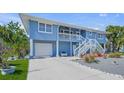 Charming two-story home with a blue exterior, white stairs, and well-maintained landscaping at 691 Gulf Bay Rd, Longboat Key, FL 34228