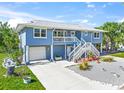 Charming two-story blue home with a double staircase, garage, and well-maintained landscaping at 691 Gulf Bay Rd, Longboat Key, FL 34228