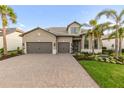 Charming gray home featuring a brick driveway, well-kept lawn, and palm trees at 7717 Mainsail Ln, Sarasota, FL 34240