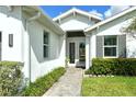 Inviting entrance to a home featuring a well-kept garden and a stone pathway leading to double glass doors at 7744 Sandhill Lake Dr, Sarasota, FL 34241
