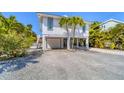 Inviting stilt home featuring a well-maintained gravel driveway and lush tropical landscaping at 123 Hammock Rd, Anna Maria, FL 34216