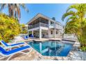 Inviting pool area with sun loungers, surrounded by lush tropical landscaping and white picket fence at 123 Hammock Rd, Anna Maria, FL 34216