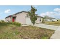 Tan home with a red front door, complemented by a well-maintained lawn and fresh landscaping at 16621 Sunburst Lake St, Wimauma, FL 33598
