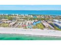 Aerial view of beachfront condo complex with a sparkling pool, lush landscaping, and direct beach access at 1945 Gulf Of Mexico Dr # M2-110, Longboat Key, FL 34228