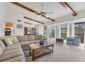 Spacious living room with beamed ceilings, a fan, and a sliding glass door leading to a balcony at 2446 Clubhouse Cir # 202, Sarasota, FL 34232