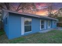 Side view of a blue single-story home with white trim, large windows, and green grass at 4015 11Th W Ave, Bradenton, FL 34205