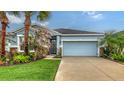Charming single-story home with a well-manicured lawn, featuring a two-car garage and colorful landscaping at 5068 Inshore Landing Dr, Apollo Beach, FL 33572