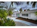 Charming single-story home featuring a white brick exterior, mature landscaping, and a welcoming entryway at 552 Juan Anasco Drive, Longboat Key, FL 34228