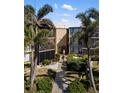 Exterior view of Sandpiper condo unit with mature landscaping, screened balconies, and walkways at 618 Bird Bay S Dr # 118, Venice, FL 34285
