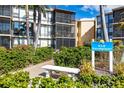Exterior of Sandpiper condo unit showing building number, landscaping, seating and screened balconies at 618 Bird Bay S Dr # 118, Venice, FL 34285