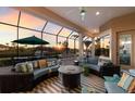Covered outdoor living area with comfortable seating overlooking a waterfront view and a colorful sunset at 11739 River Shores Trl, Parrish, FL 34219