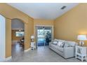 Cozy living room with tile flooring, comfortable seating, and sliding doors leading to the pool area at 12022 Granite Woods Loop, Venice, FL 34292