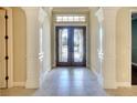 Elegant foyer with decorative glass double doors, large tiled floor and white pillars at 15403 Leven Links Pl, Lakewood Ranch, FL 34202