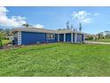 This home boasts an expansive green lawn and a blue exterior paint scheme perfectly complemented by a grey tile roof at 2434 Carlisle Pl, Sarasota, FL 34231
