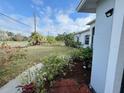 Lush front yard with blooming red flowers, manicured greenery, and a view of the street on a beautiful day at 3650 S Sumter Blvd, North Port, FL 34287