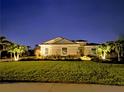 Night view of a cozy home illuminated with landscape lighting and lush tropical landscaping at 4772 Vasca Dr, Sarasota, FL 34240