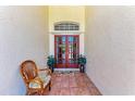 Cozy outdoor entryway with tiled floor, rattan chair, and red double doors at 5103 73Rd E St, Bradenton, FL 34203