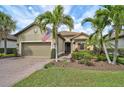 Charming single-story home featuring a paver driveway, attached garage and lush tropical landscaping at 5656 Cantucci St, Nokomis, FL 34275