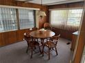 Warm dining room with wood-paneled walls, a round table, and natural light from large windows at 618 51St W Ave, Bradenton, FL 34207