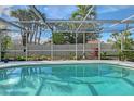 Sparkling pool enclosed by a screen enclosure, surrounded by lush landscaping for privacy and relaxation at 6684 Easton Dr, Sarasota, FL 34238