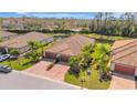 Aerial view of a charming home with tile roof, three-car garage, lush landscaping, and a serene pond view at 6716 Willowshire Way, Bradenton, FL 34212