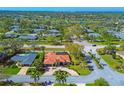 A serene aerial view shows a neighborhood featuring lush trees and a beautiful single-story home with a red tile roof at 6900 Country Lakes Cir, Sarasota, FL 34243