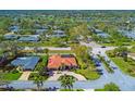 Beautiful aerial view of a home with a red tile roof surrounded by lush landscaping and mature trees in a quiet neighborhood at 6900 Country Lakes Cir, Sarasota, FL 34243