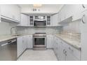 Bright kitchen featuring white cabinets, granite countertops, stainless steel appliances, and a modern backsplash at 800 Hudson Ave # 102, Sarasota, FL 34236