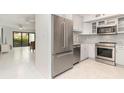 Stainless steel refrigerator overlooking living area and kitchen with white cabinets and modern stainless appliances at 800 Hudson Ave # 102, Sarasota, FL 34236
