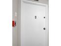Image of the front door featuring a white door, silver hardware, and an emergency alarm box at 1001 Beach Rd # A203, Sarasota, FL 34242