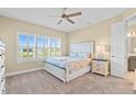 Cozy bedroom with a large window, ceiling fan, and a comfortable bed with decorative pillows at 11127 Devonbridge Dr, Palmetto, FL 34221