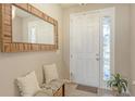 Cozy entryway featuring a decorative mirror, seating, and a stylish front door at 15008 Trinity Fall Way, Bradenton, FL 34212