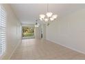 An empty living area with neutral tile flooring, fan and chandelier at 1663 San Silvestro Dr, Venice, FL 34285