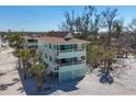 Beach house exterior featuring multi-level balconies, palm trees, and access to a sandy beach at 2350 N Beach Rd # 1B, Englewood, FL 34223