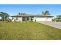 Beautiful single-story home with a three-car garage, green lawn, and a striking red front door at 25259 Alcazar Dr, Punta Gorda, FL 33955