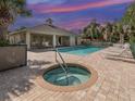 Community pool with a hot tub, chaise lounges, and tropical landscaping on a sunny day at 403 Auburn Lakes Cir # 403, Venice, FL 34292