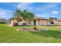 Well-manicured lawn and landscaping enhance this single-story home's curb appeal, complemented by mature palm trees at 447 Pineview Dr, Venice, FL 34293