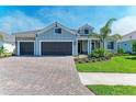 Charming single-story home with a three-car garage, manicured lawn, and a brick paved driveway at 8046 Anthirium Loop, Sarasota, FL 34240