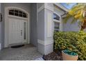 Close-up of the front door, featuring decorative glass and an arched transom window with stylish trim work at 8420 Sailing Loop, Lakewood Ranch, FL 34202