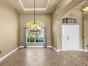 Bright living room featuring a decorative chandelier, large window, and neutral tile flooring at 8420 Sailing Loop, Lakewood Ranch, FL 34202