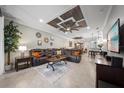 Open living room with leather sofa, tray ceiling, and views to dining and kitchen areas at 12151 Amica Loop, Venice, FL 34293