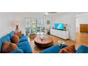 Bright living room with wood floors, a blue sofa, and sliding glass doors leading to the outside at 1600 1St W Ave # 102A, Bradenton, FL 34205