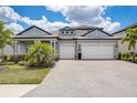 Charming home featuring a paved driveway, manicured lawn, and a two-car garage, under a beautiful, partly cloudy sky at 19912 Bridgetown Loop, Venice, FL 34293