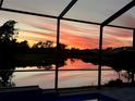 Picturesque sunset view over a tranquil lake from the screened-in pool area, offering a serene atmosphere at 19912 Bridgetown Loop, Venice, FL 34293