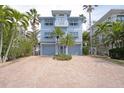 Lovely two-story home with three car garage and a paver driveway, accented by tropical palm trees at 2407 Avenue A, Bradenton Beach, FL 34217