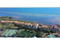 Aerial view of complex with red tiled roofs, tennis courts, pool, and waterfront location at 4535 Bay Club Dr, Bradenton, FL 34210
